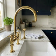 Unlacquered brass bridge kitchen faucet with cross handles and separate hand sprayer