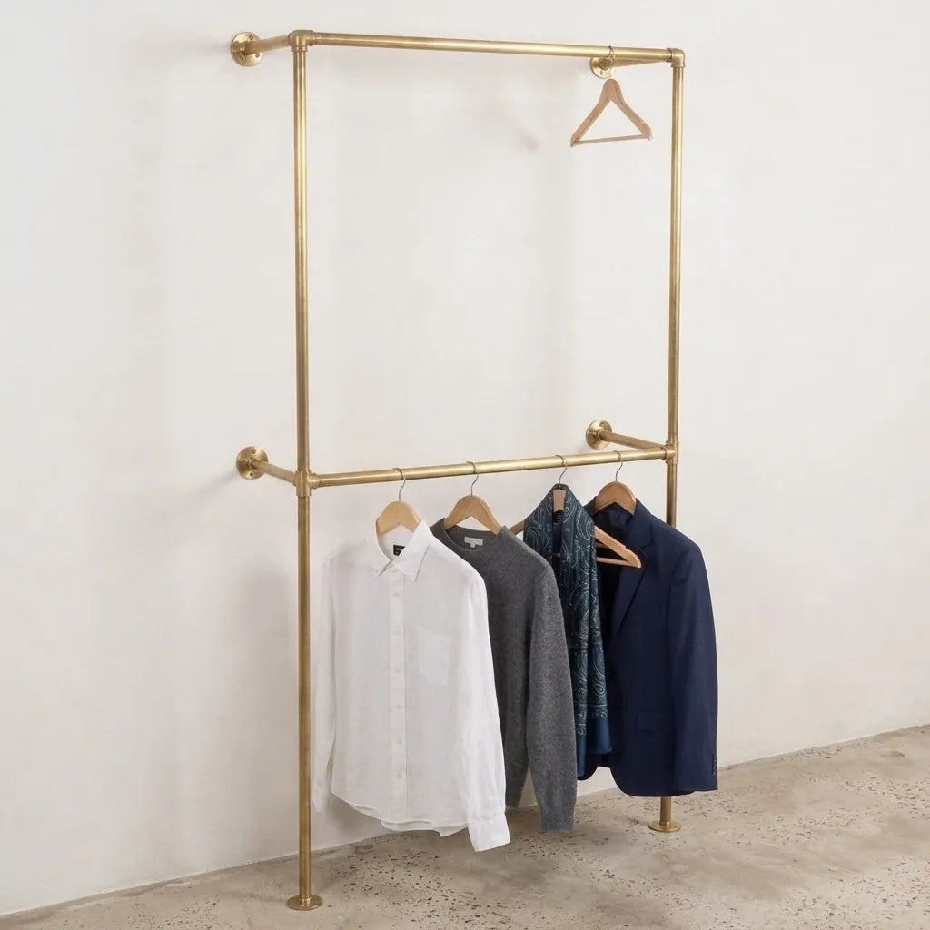 Solid brass floor to wall garment rack with double hanging rails for open wardrobe storage.