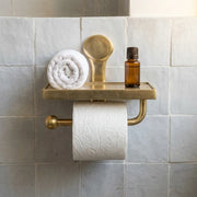Wall mounted brass toilet paper holder with integrated storage shelf for bathroom essentials and toiletries