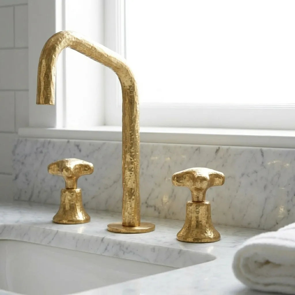 Handmade brass vanity faucet featuring a faceted spout and matching hammered handles for luxury bathroom interiors