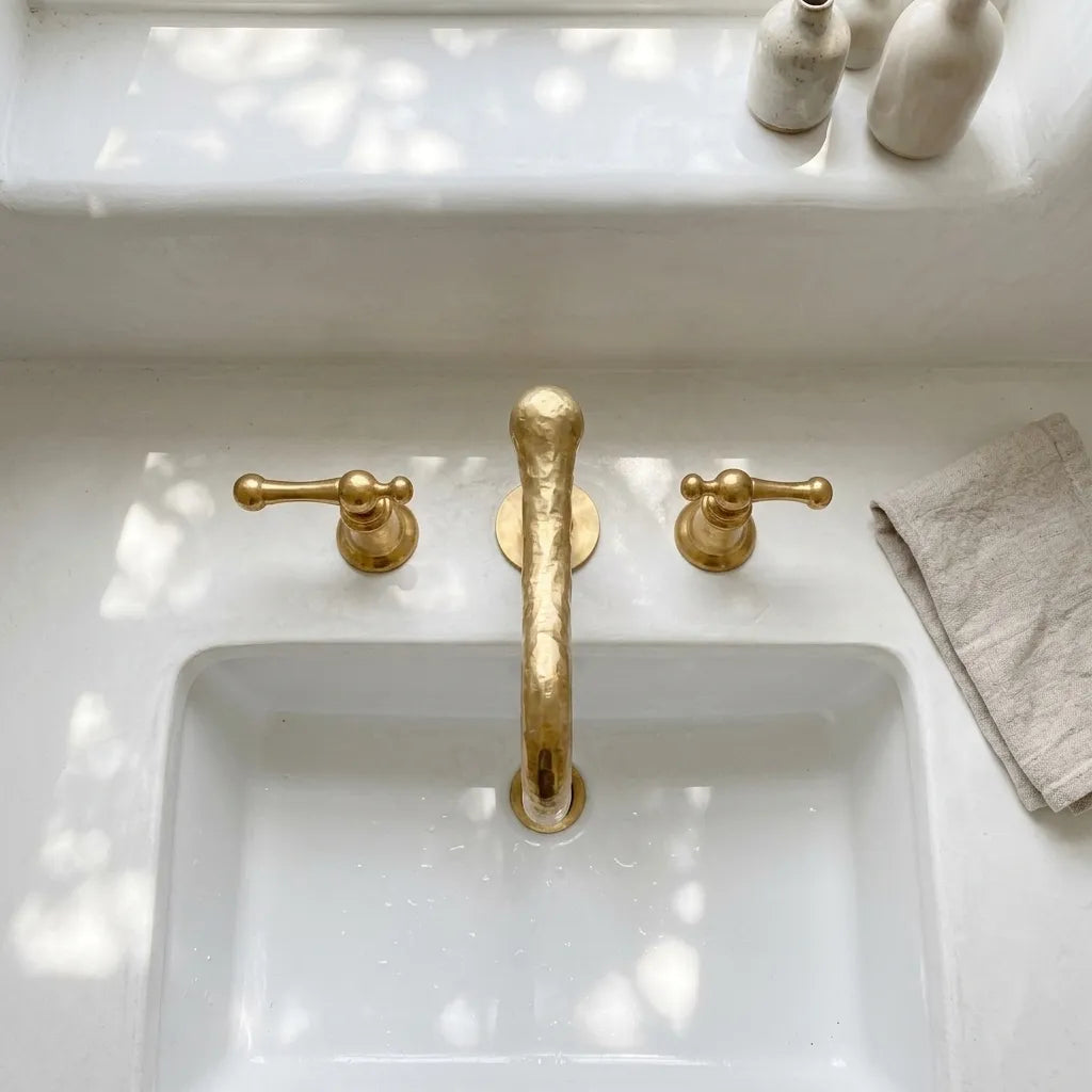 Luxury brass sink faucet with artisan forged detailing, curved neck spout, and traditional crossbar handles