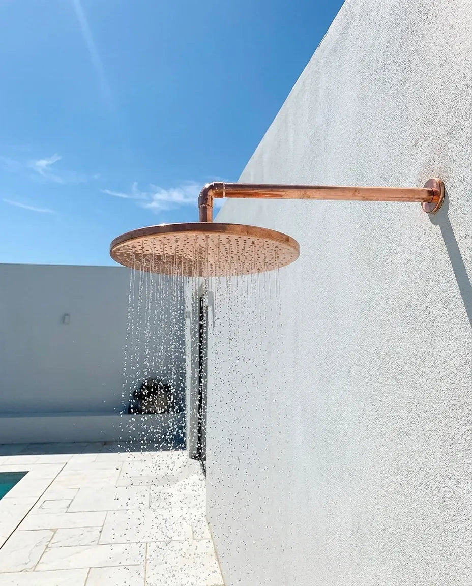 Solid copper rain shower head featuring a hammered finish and wide spray pattern for spa-inspired bathing.