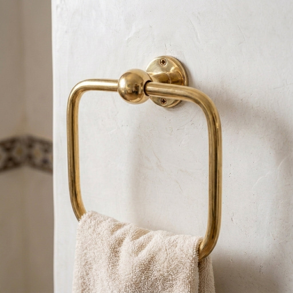 Solid brass square hand towel loop mounted on a bathroom wall with a white towel.