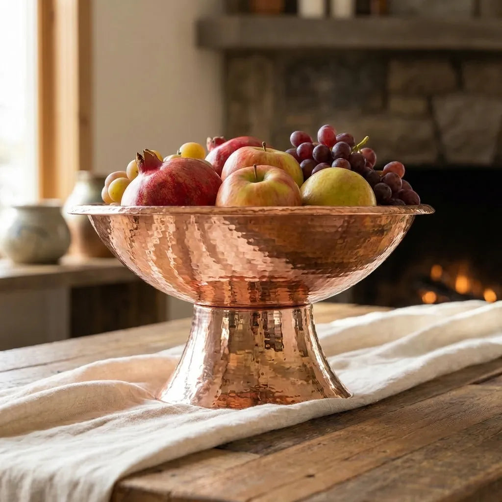 Decorative hammered copper pedestal bowl for serving fruit or creating a timeless kitchen and dining room centerpiece.