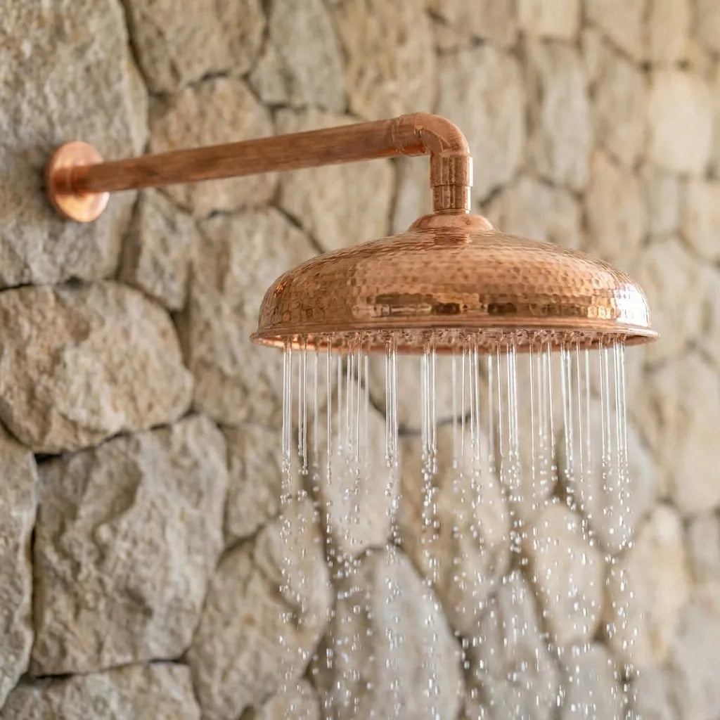 Hammered Copper Outdoor Rain Shower Head with Wall Mounted Arm on Stone Wall