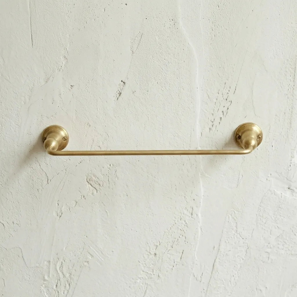 Traditional brass towel holder featuring rounded wall brackets and a warm living finish for elegant bathroom storage