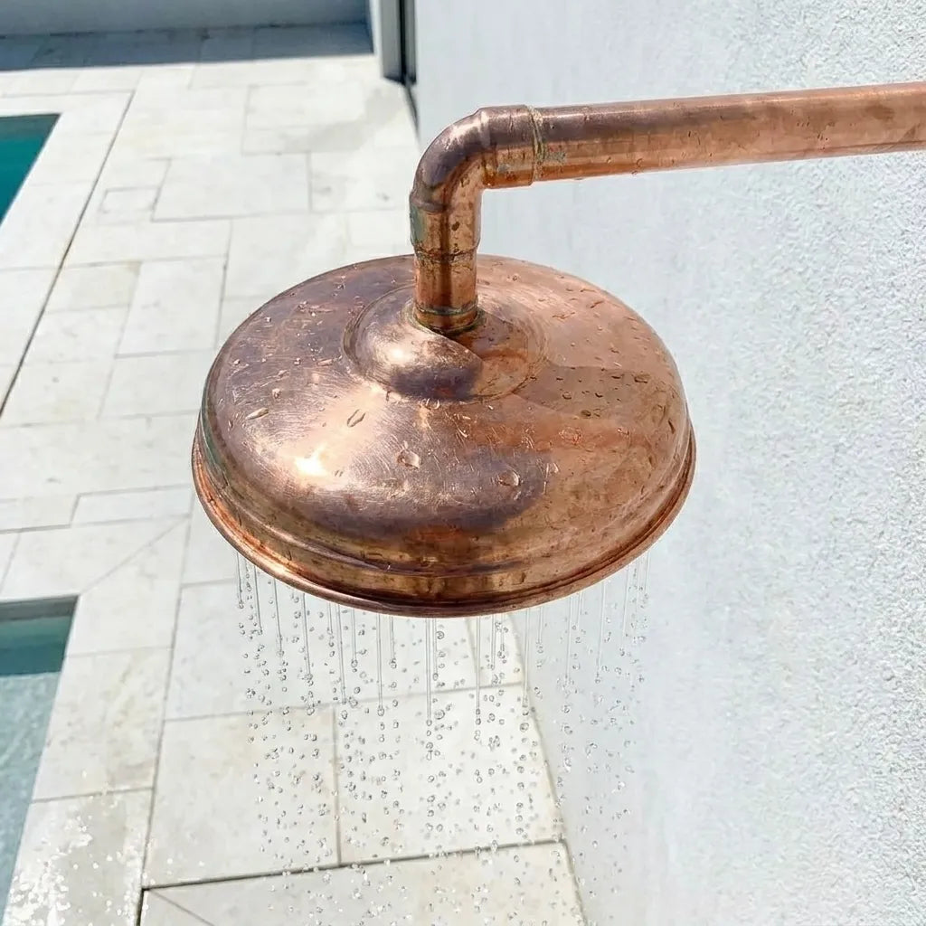 Artisan hammered copper rainfall shower head featuring a wide spray face and handcrafted rustic finish.