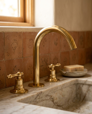Brass widespread bathroom faucet with high-arc spout on marble vanity