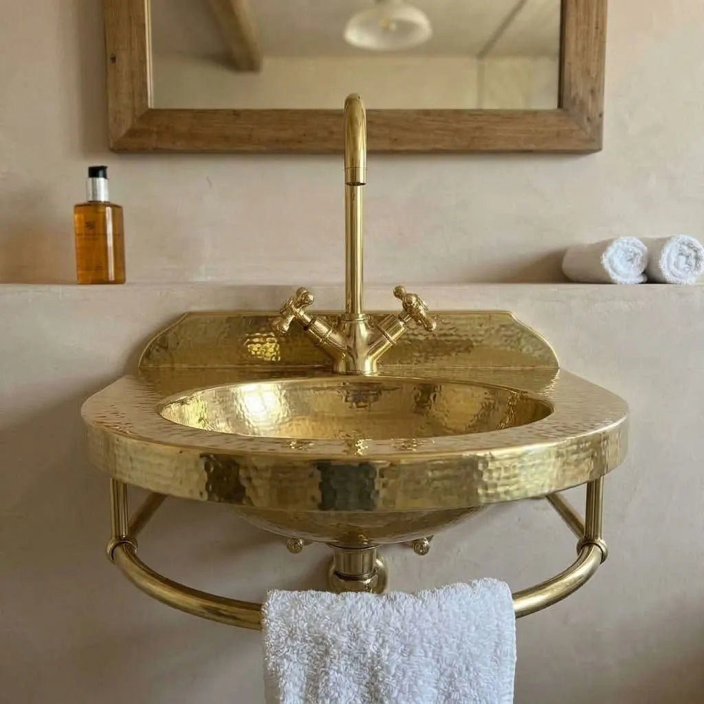 Front view of wall-mounted hammered brass sink with curved towel rail and raised backsplash