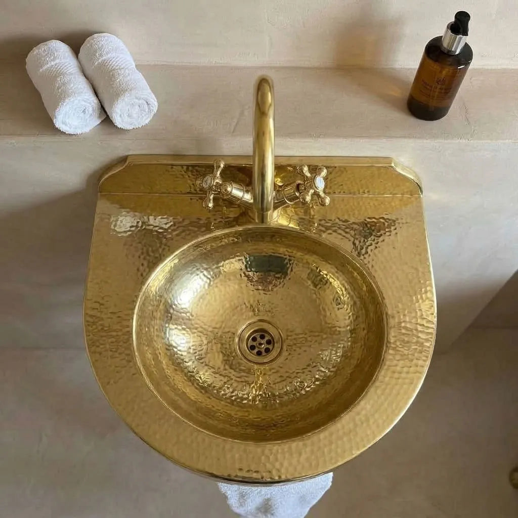Top view of hammered brass wall-mounted basin with backsplash, faucet and drain