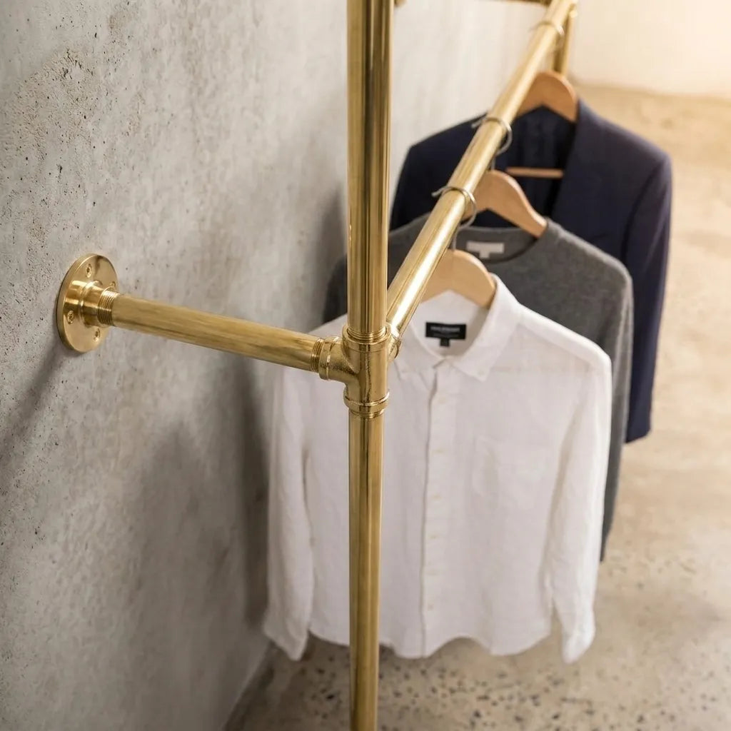 Custom brass clothing rack with floor supports and dual hanging levels for walk-in closets.