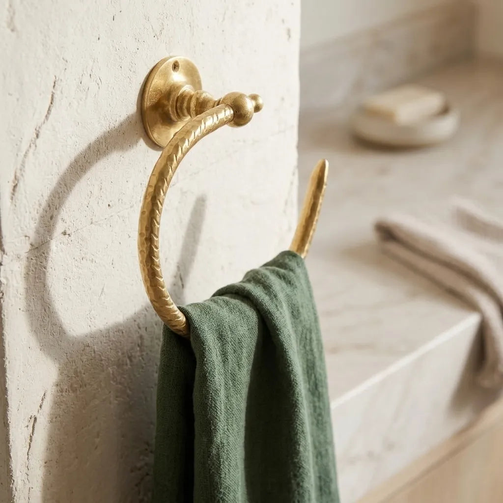 Open brass hand towel holder with hammered finish displaying a green linen towel