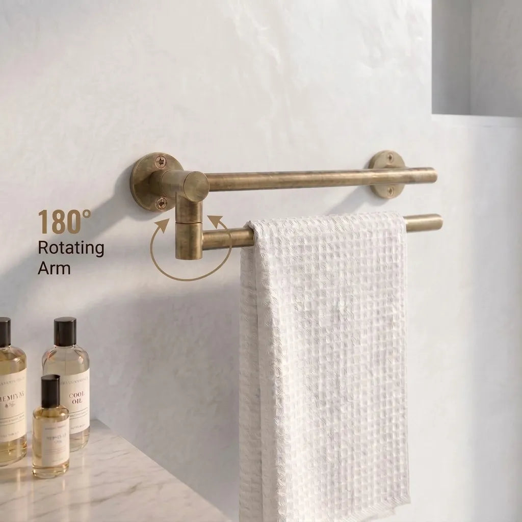 An antique brass double towel bar with a rotating arm, mounted on a white tiled wall. A white textured towel is hanging from the lower bar.