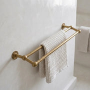 Solid brass double towel bar with rounded ball-end supports mounted on a bathroom wall, holding a textured white waffle towel.