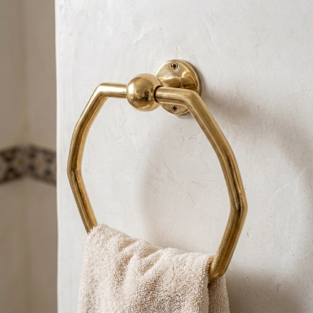Solid brass octagonal hand towel loop mounted on a bathroom wall with a white cotton towel.