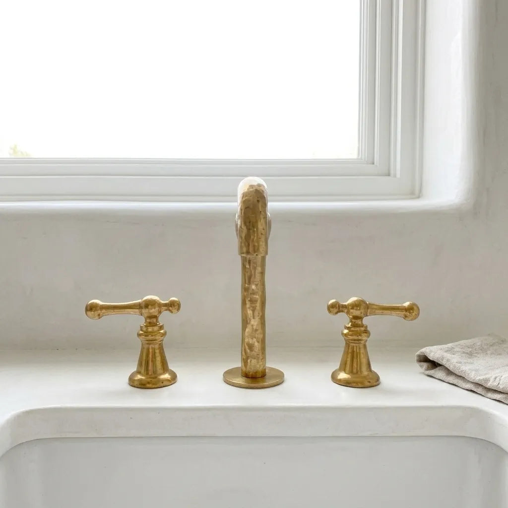 Designer brass vanity faucet with handcrafted metal finish and elegant architectural silhouette for upscale bathrooms