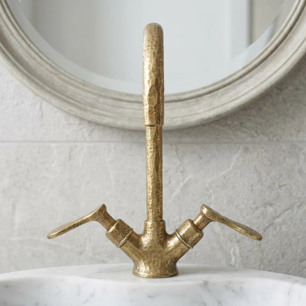 Solid brass vanity mixer tap with decorative hammered detailing and dual lever controls beside a stone vessel sink