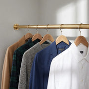 Solid brass wall-to-wall closet rod installed between two walls with hanging garments.