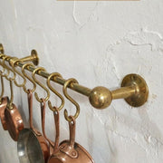 Brass pot rack with copper pots on a white wall