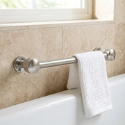 Polished chrome towel rail mounted on a natural stone bathroom wall