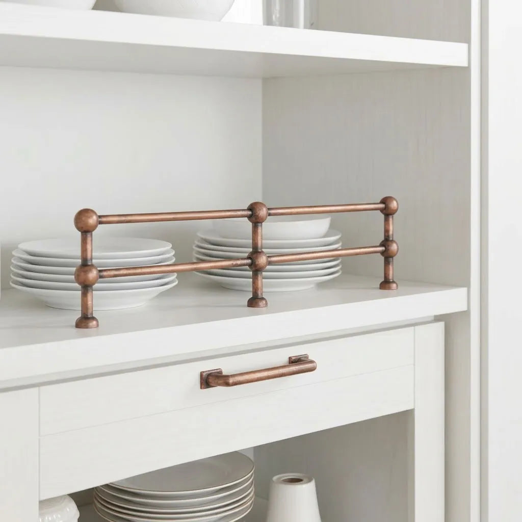 Solid brass sphere gallery rail in an aged copper finish installed on open shelving