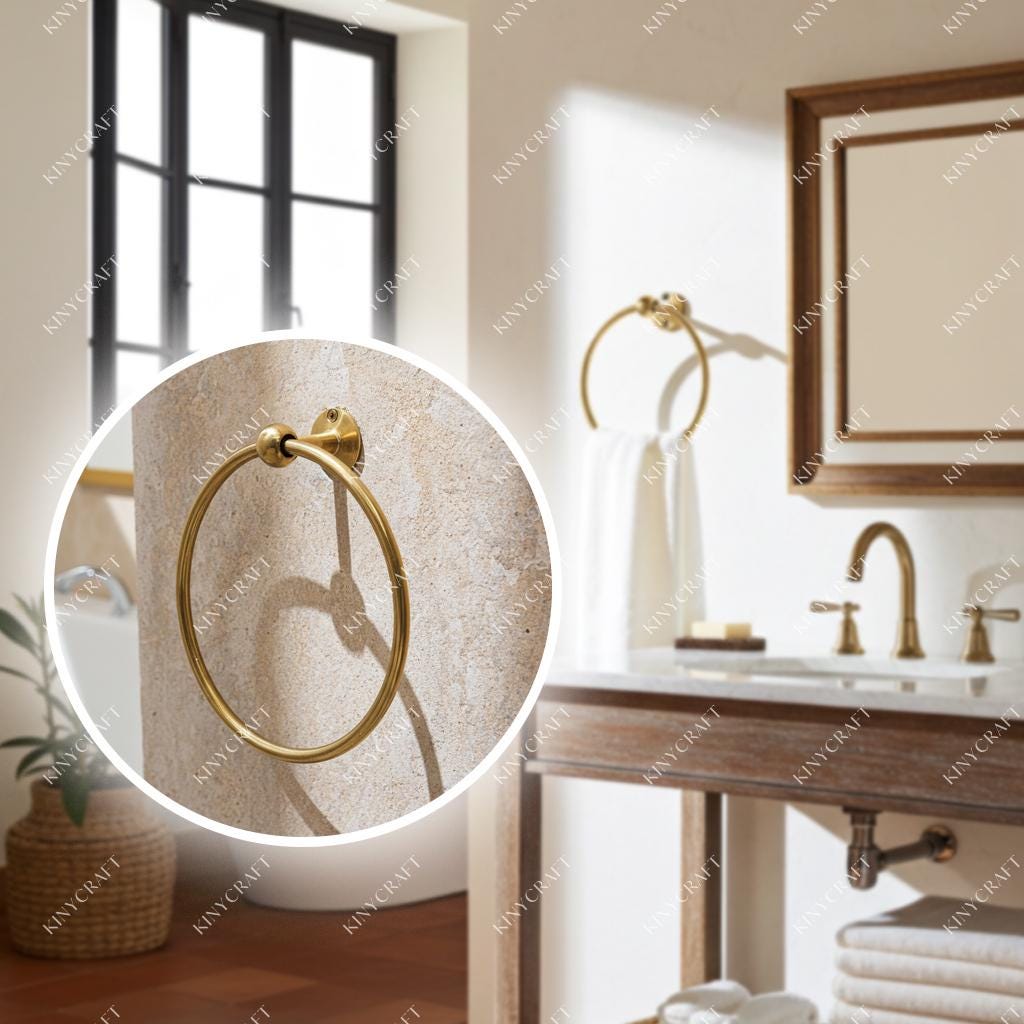 Round solid brass towel holder for hand towels beside a bathroom vanity.
