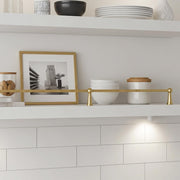 Handmade solid brass shelf rail installed on a white floating kitchen shelf.
