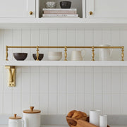 Solid brass gallery rail installed on a white floating kitchen shelf.