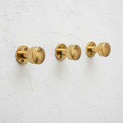 Set of solid brass wall hooks with hammered round knobs for coats, towels, robes, hats, and bags.