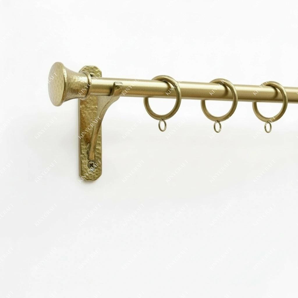 Luxury brass curtain rod featuring hammered wall-mounted brackets, curtain rings, and classic end finials.