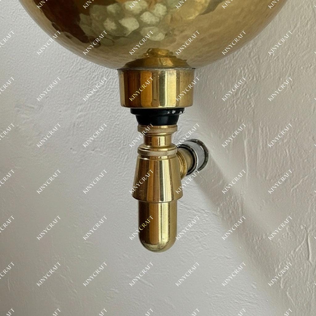 Round hammered brass wall-mounted bathroom sink featuring a handcrafted textured finish.