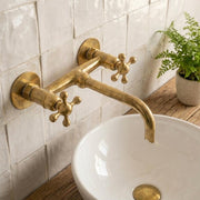 Unlacquered brass wall mounted bathroom faucet with cross handles
