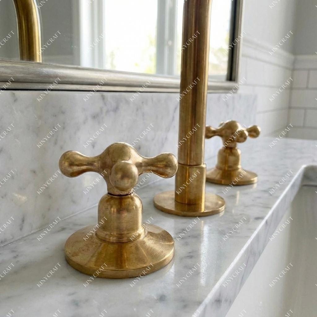 Warm brass widespread sink faucet mounted on white marble countertop with classic bathroom design.