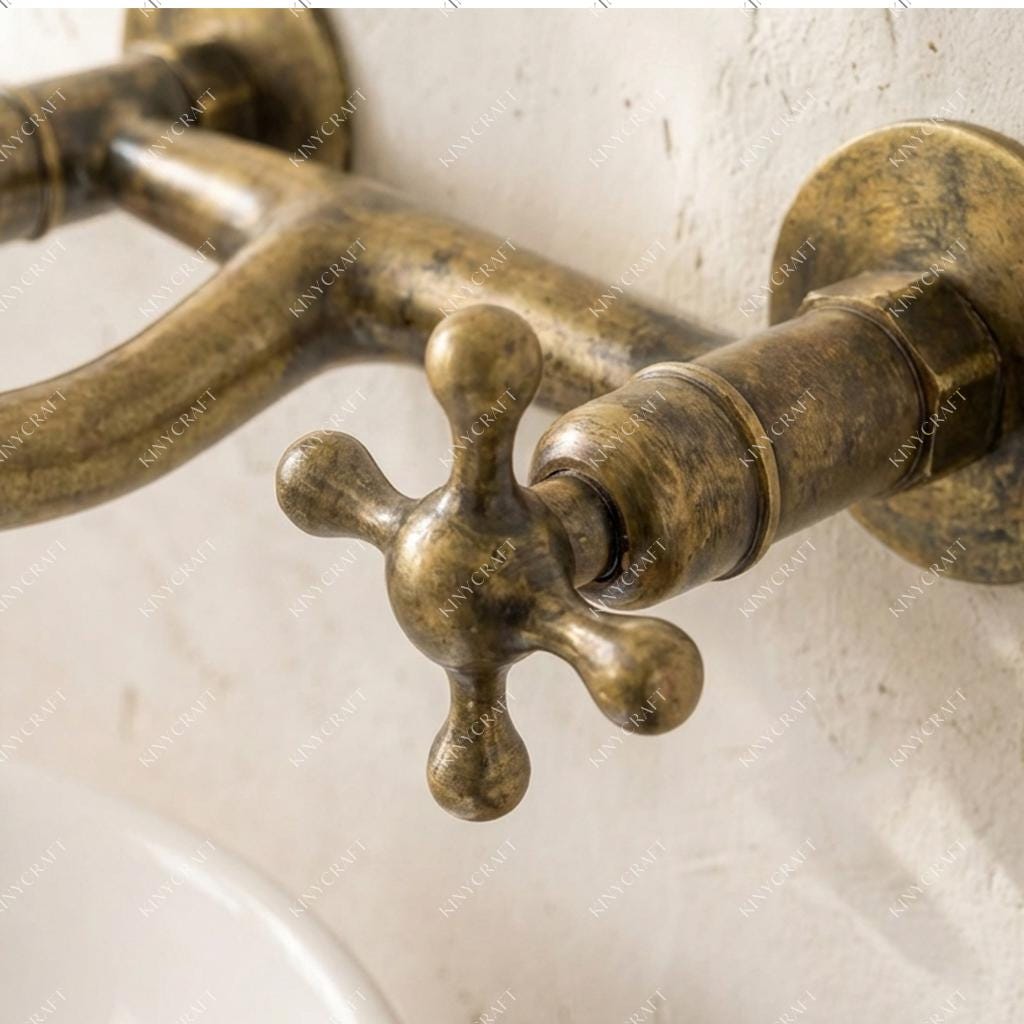 Vintage-inspired wall mount brass faucet with aged finish for farmhouse bathrooms.