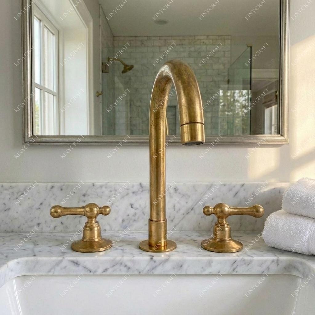 Handcrafted solid brass three-piece bathroom faucet with aged brass living finish.
