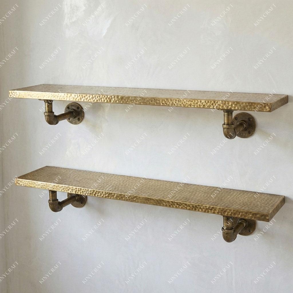 Solid brass wall shelf with exposed pipe brackets showcasing decorative accessories and glass jars.
