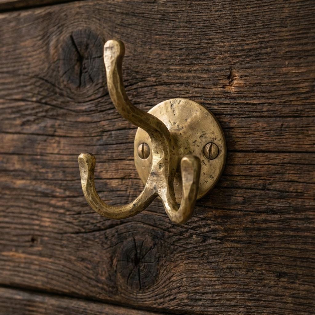 Vintage brass coat hook with three curved prongs for entryway and mudroom storage.