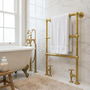 Deck-mounted heated solid brass towel rail holding a white bath towel.